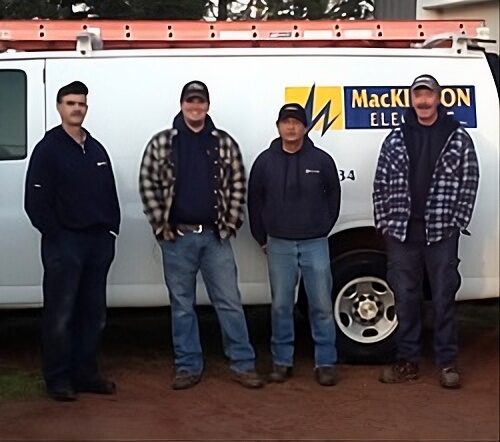 Four MacKinnon Electric electricians beside a company van